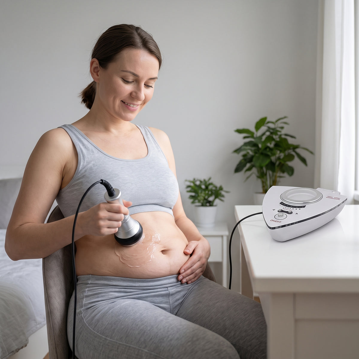 Woman using the 40k cavitation handpiece on her abdomen at home.